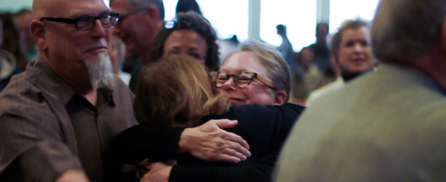 People gathered in a room and embracing one another.